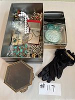 Box of assorted necklaces, black gloves and decorative mirror visible in the image, showing lots of beaded and shell-piece necklaces.
