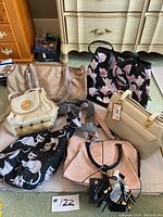 Overview of six purses arranged on floor, showing variety of styles, colors, and prints.