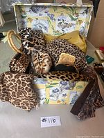 Open small floral-patterned trunk filled with various leopard print accessories including bags, scarves, and more.