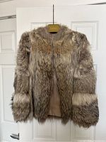 Front view of vintage fur coat with sleeves, showing natural brown and grey fur and leather lining inside.