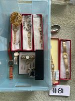 Photo of plastic bin containing various gold-tone and multi-colored watches and bracelets, some in jewelry boxes, showing overall lot contents.