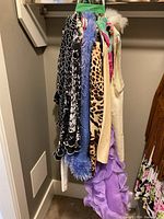 Seven assorted women's clothing items on hangers featuring varied patterns and textures