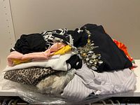 Pile of assorted women's tops in solid colors, animal print, floral and striped fabrics.
