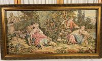 Wide view of full framed tapestry showing romantic pastoral scene with couples, cherubs, and landscape under an ornate detailed carved wooden frame.