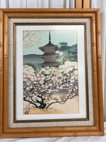 Framed print displaying a colorful scene of a blossom tree and pagoda, with measurement details visible