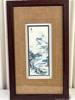 Full view of framed Asian nature print showing vertical blue landscape with mat and dark wood frame.