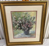 Full view of the framed Monet print showing the floral arrangement and the gold decorative frame with glass.