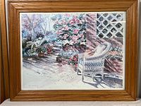Full view of the framed print showing a garden scene with white wicker chair and flowers.