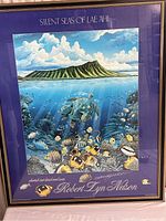 Full view of framed poster with underwater scene and island above water, poster title at top and artist name at bottom.