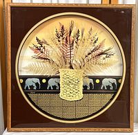 Full frontal image of vintage Thrasher shadowbox art showing the woven basket with dried ferns and elephant motif border inside wooden frame.