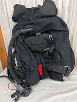 Front and side view of the black Zeagle diving backpack buoyancy compensator with straps and hoses visible