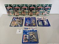Lot of 12 baseball figures in original packaging, grouped and laid out showing both Starting Lineup and Headliners series with packaging wear.