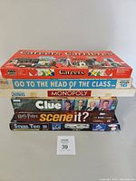 Stacked board games from Careers, Go To The Head of the Class, Monopoly, Clue, Harry Potter Scene It, and Steel Tec building set.