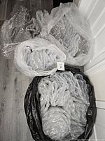 Four large bags filled with assorted bubble wrap sheets and rolls, visible on a wood floor.