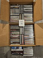 Two boxes open showing over 100 CDs stacked and packed in jewel cases. CDs are varied with classic artists primarily in jazz and big band genres.