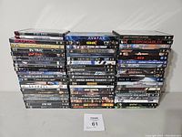 Full view of stacked assorted DVDs in cases showing 52 titles in lot