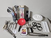 Full view of all kitchen items including electric wine opener, strainer, tongs, utensils, flatware, thermometer, egg rings, and ice cube tray