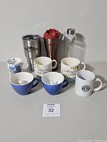 Full view of all mugs and travel drinkware included in the lot as displayed on a flat surface.