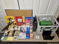 Photo showing the entire lot including cork board, tabletop stapler, file crate, calculator, binders, labels, pens, and paper items.