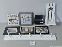 Full view of the assorted wall art items with white coat hanger displaying three framed photos and other decor pieces arranged behind