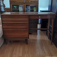 Full front view of solid maple desk showing four drawers and tapered legs.