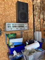 Shelf-mounted receiver and single bookshelf speaker against particle board wall