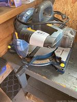 Front view of Mastercraft mitre saw showing handle, blade guard, power cord, and base with angle scale.