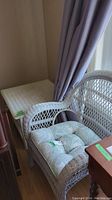 Photo showing white painted wicker armchair with light blue-green tufted cushion featuring sea life patterns.