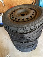 Stack of four Goodyear winter tires mounted on steel rims, showing tread and rim condition.