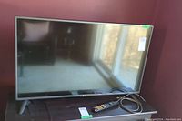 Front view of the 42-inch LG TV with stand, remote shown in front.