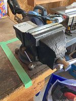 Single Maxtech bench vice mounted on a workbench, showing the rough black cast iron body and serrated jaws.