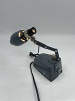 Full side view of Bausch & Lomb microscope lamp showing adjustable arm, lamp head with gold accents, and power cord.
