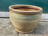 Side view of the glazed ceramic planter pot showing the rounded body and wide rim with brown glaze.