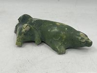 Full side view of the green soapstone seal sculpture showing the full length of the figure and flippers on one side.