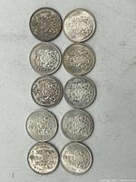 Top view of all 10 silver 50 cent coins arranged in two vertical rows, varying tones from tarnished to bright silver.