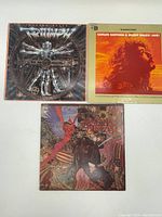 Three vintage LP albums laid flat showing front covers including Santana & Buddy Miles Live, Triumph Allied Forces, and a psychedelic art LP.