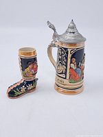 Miniature beer stein and boot shaped ceramic item, side view showing characters and decorative details
