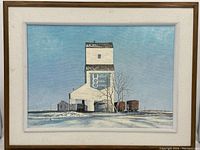 Frontal view of the framed canvas painting featuring a grain elevator under a blue sky with snow on the ground and adjacent railcars.