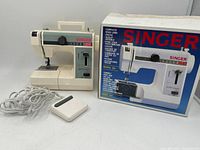 SINGER Featherweight Plus sewing machine next to its original box showing the product image and branding.
