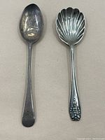 Top down view of two sterling silver spoons showing the bowls and handles of both spoons