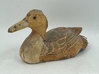 Side angle view showing carved feather details and painted head with natural brown and tan hues