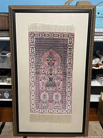 Full view of framed Persian silk rug mounted on a linen mat.
