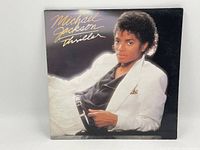 Front cover of Michael Jackson Thriller LP, showing Michael in white suit with black shirt and gold signature text.