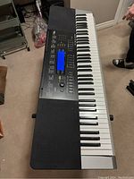 Full view of the Casio keyboard placed on an adjustable black metal stand on carpeted floor.