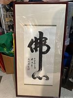 Framed piece of Chinese calligraphy artwork in black ink with signature and red seals, matted and framed behind glass.