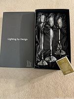 Set of three crystal candlestick holders in original black box with satin lining, showing all items and informational card included.