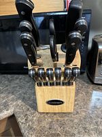Front view of the wooden knife block holding several knives, shears, and sharpening steels with Cuisinart logo on block
