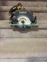 Front view of the Dewalt 60V cordless circular saw with visible blade, green base plate, and black/yellow handle on carpeted steps.
