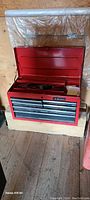 Front view of closed red metal Husky toolbox sitting on wood surface
