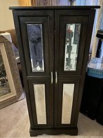 Front view of tall two door wooden jewelry cabinet with four rectangular mirrors on doors